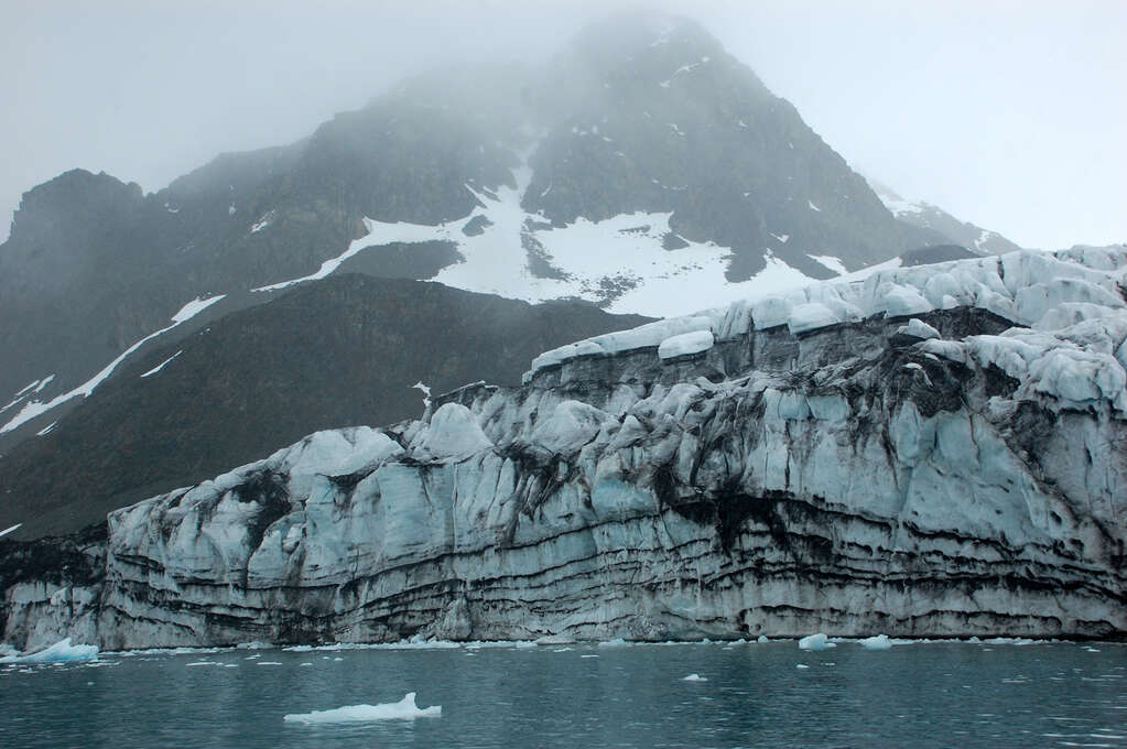 A glacier with layers of black volcanic ash.