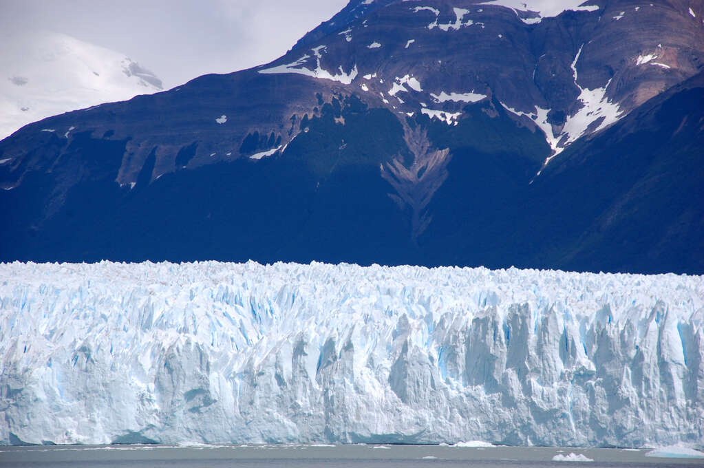 A wall of ice that leads into the background with an even larger mountain behind it.