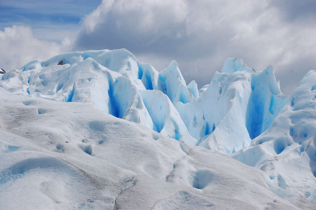 Patches of white ice with dark blue glows coming from the crevices.