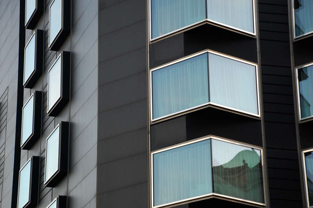 The side of a building with many windows of different shapes and angles.