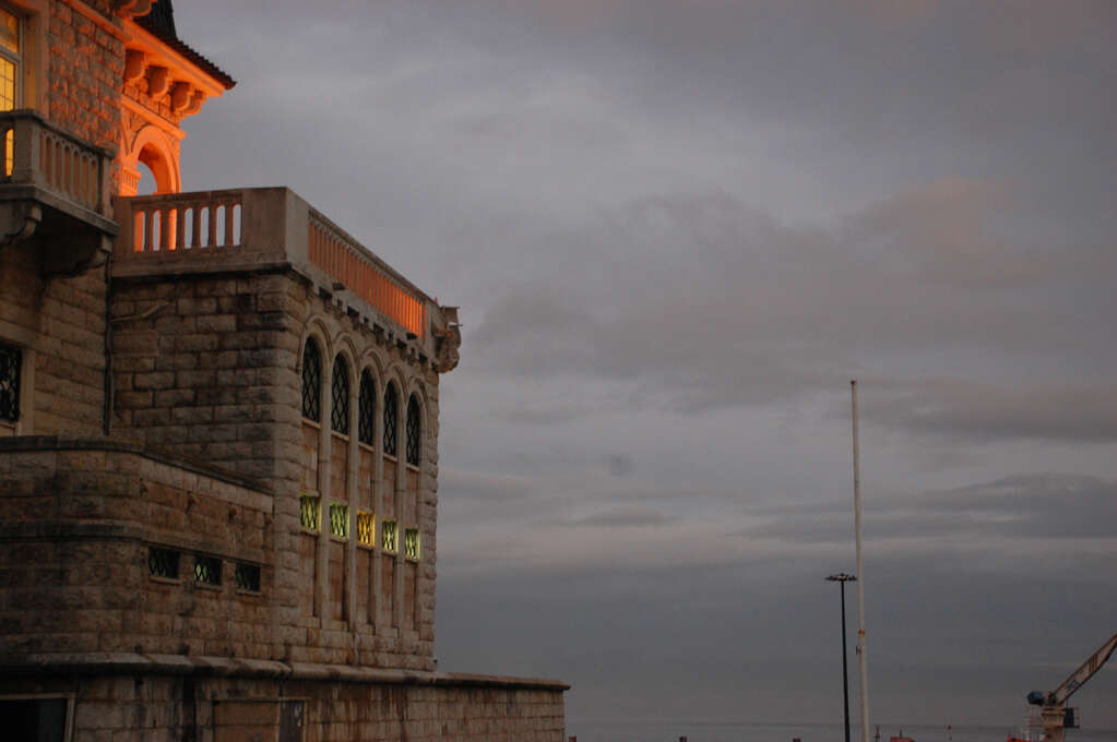 A gray sky and a stone building on the left with a glow coming from out of frame.