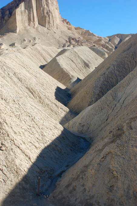 A shadow along the base of a small valley between wavy rocks.