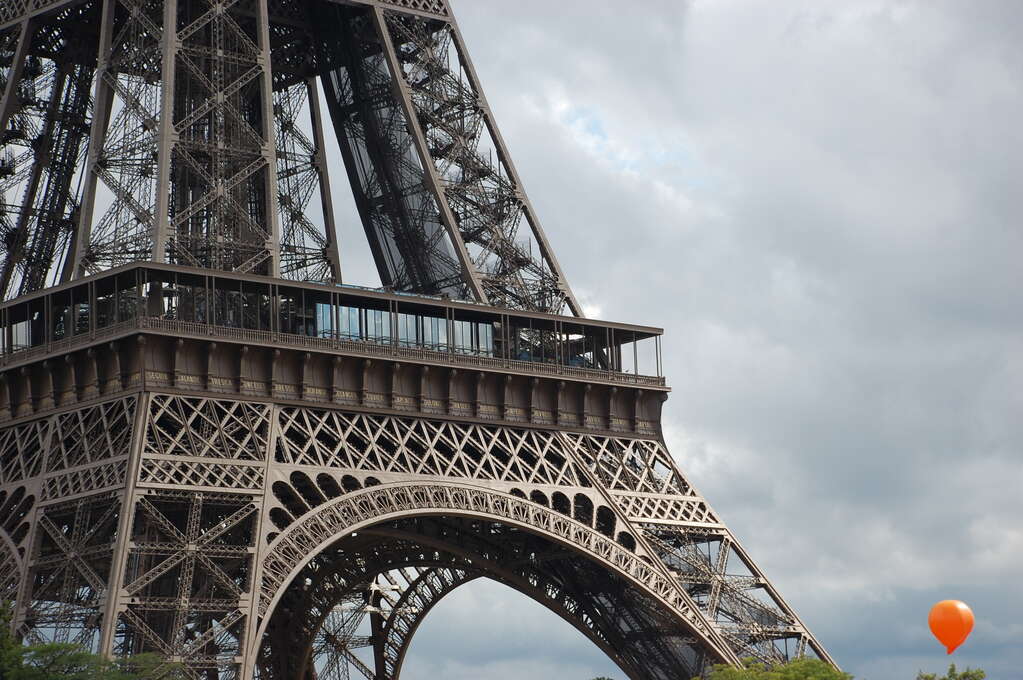 The lower half of the Eiffel Tower taking most of the frame and an orange balloon in the bottom right.