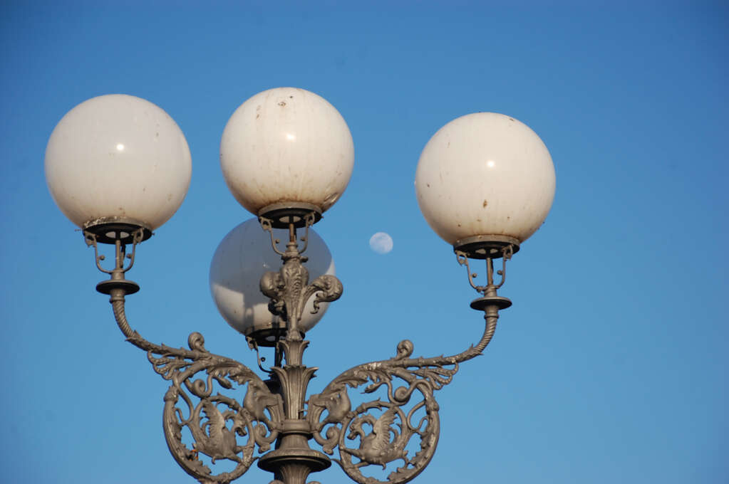 A lamp with four arms each with a white orb. The moon sits between the arms.