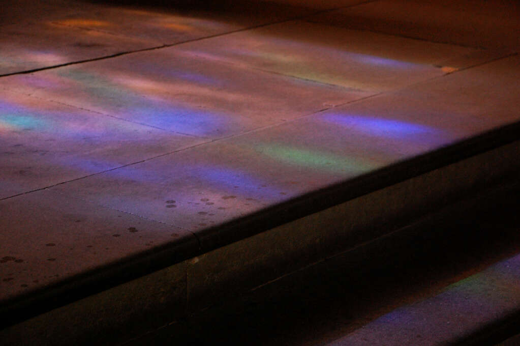 Colorful lights from a stained glass window scattered on some steps.