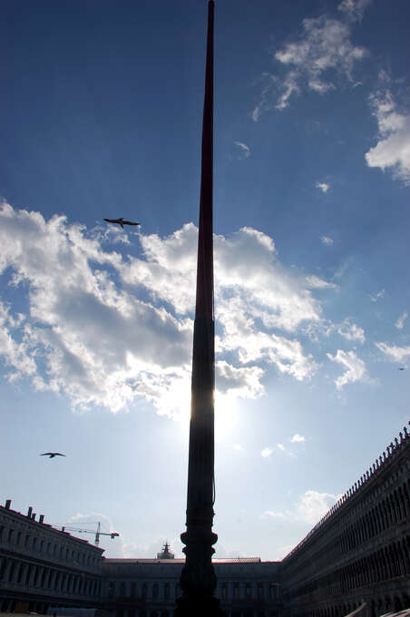 A large pillar in the center blocking the sun with a large open square on either side.