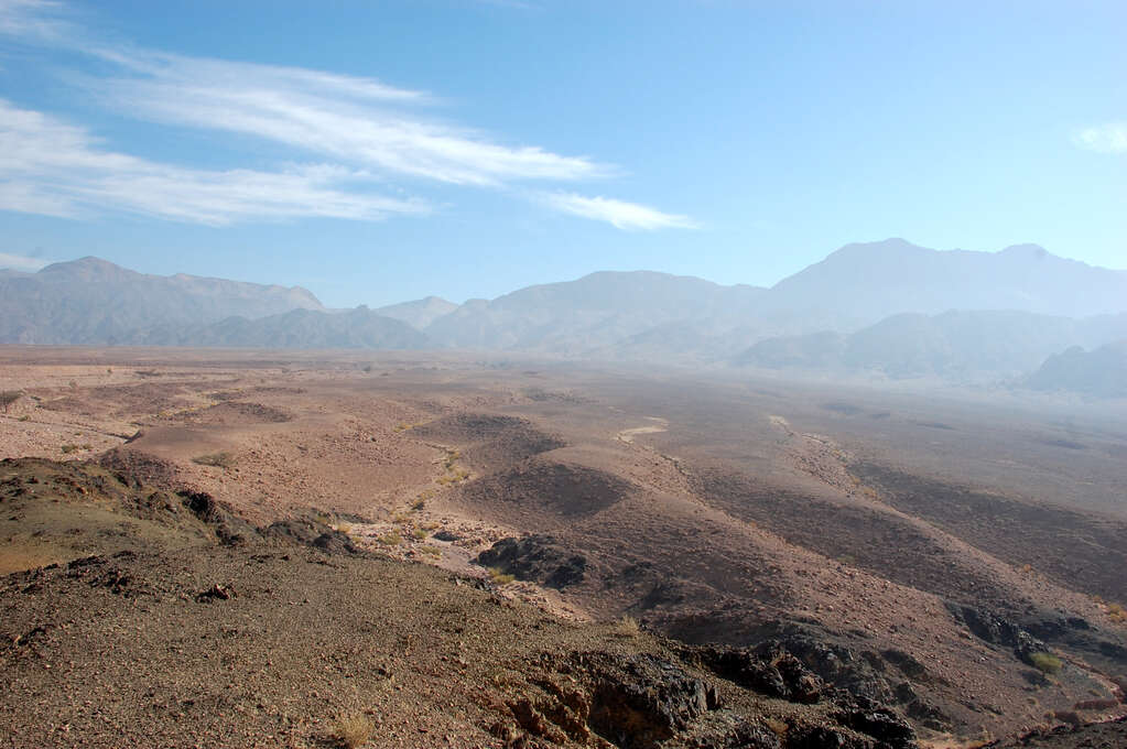 A wide view of mostly empty desert with mountains in the background.