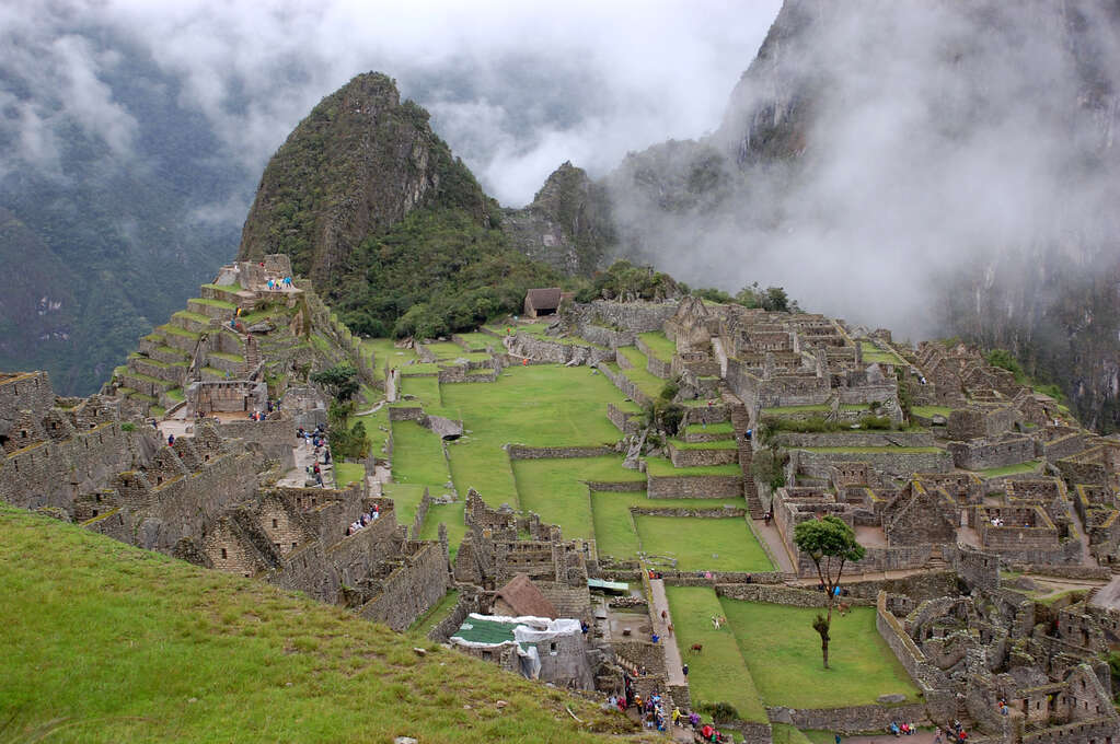 A high view of a grassy, tiered, ancient city made of stone.