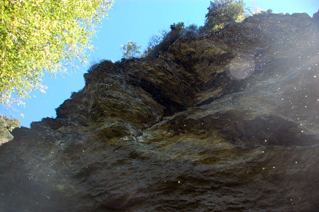 Water droplets falling from a cliff above.