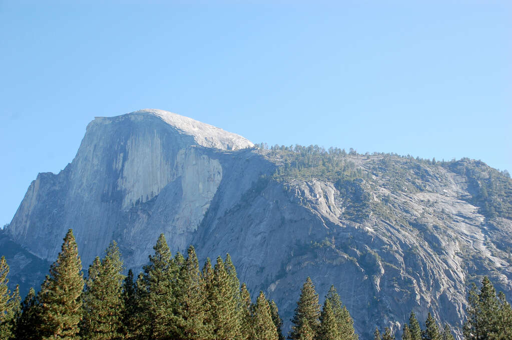 A large rocky mountain in the distance with a curved slope on top.